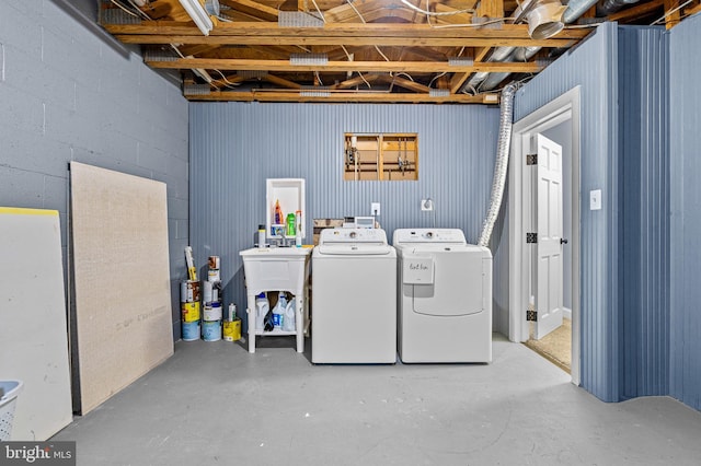 washroom with concrete block wall and independent washer and dryer