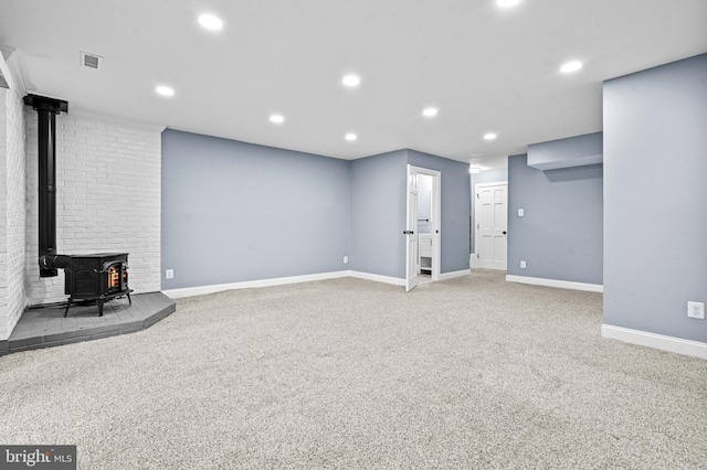 basement featuring recessed lighting, carpet flooring, visible vents, baseboards, and a wood stove