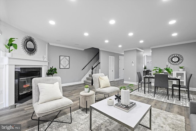 living area featuring baseboards, wood finished floors, stairs, a fireplace, and recessed lighting