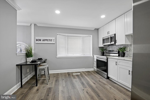 kitchen with stainless steel appliances, baseboards, decorative backsplash, and white cabinetry