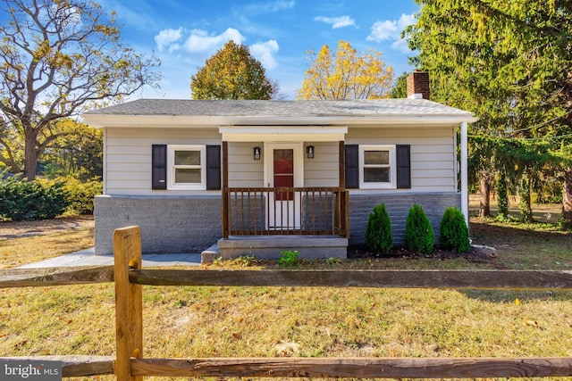 bungalow-style home with a fenced front yard, a front yard, and a chimney