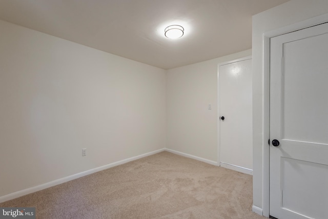 empty room featuring light colored carpet and baseboards