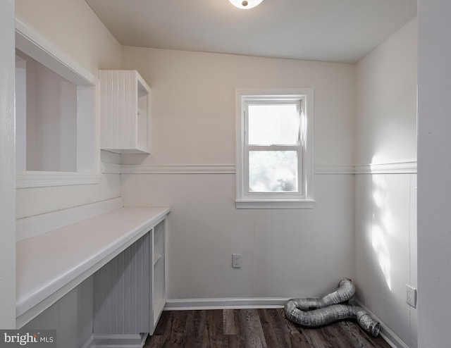 clothes washing area featuring laundry area, a wainscoted wall, and dark wood finished floors