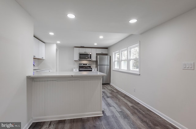 kitchen featuring baseboards, white cabinets, a peninsula, stainless steel appliances, and light countertops