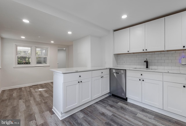 kitchen with light countertops, stainless steel dishwasher, white cabinetry, a sink, and a peninsula