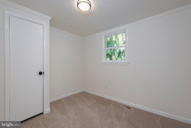 spare room with light colored carpet, visible vents, crown molding, and baseboards