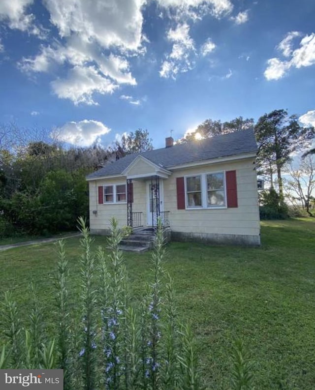 bungalow-style home with a front yard and a chimney