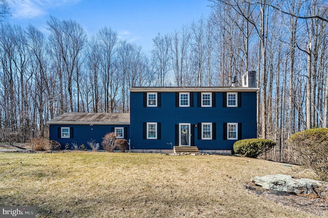 colonial-style house with a chimney and a front lawn