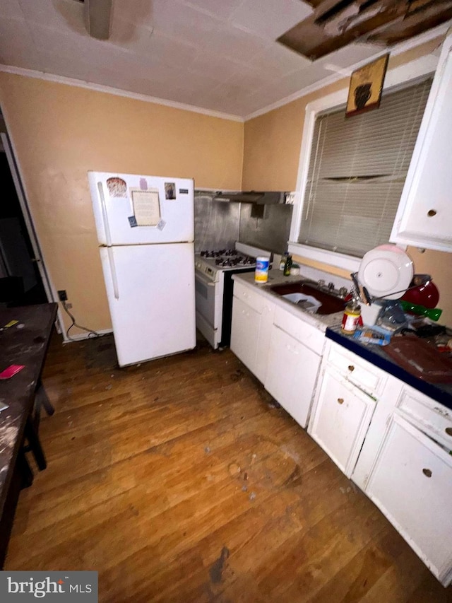 kitchen featuring dark countertops, white appliances, white cabinets, and a sink