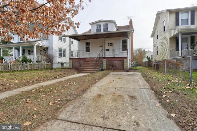 view of front facade featuring covered porch, a chimney, fence, and cooling unit