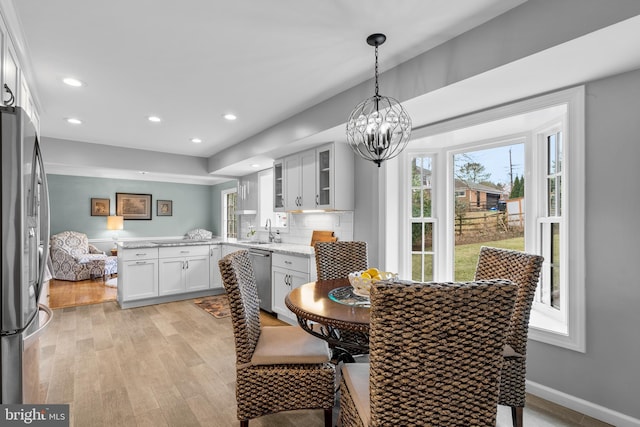 dining area featuring light wood-type flooring, a notable chandelier, baseboards, and recessed lighting