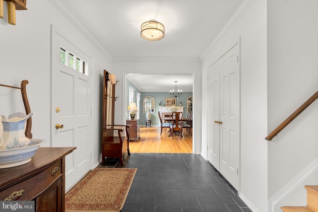 foyer with a notable chandelier, stairs, baseboards, and crown molding