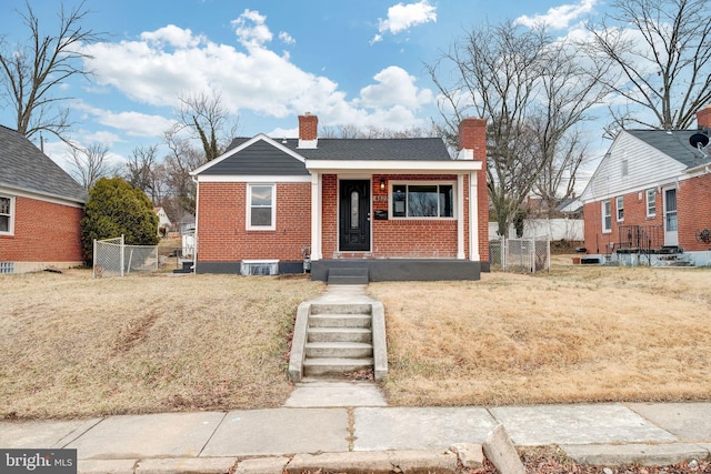 bungalow-style house with a chimney, fence, a front lawn, and brick siding