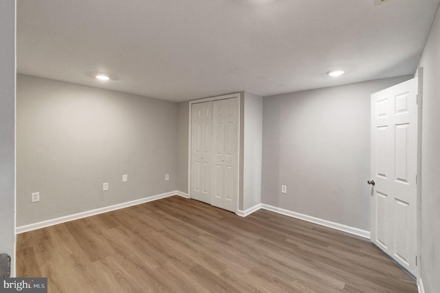 unfurnished bedroom featuring a closet, wood finished floors, and baseboards