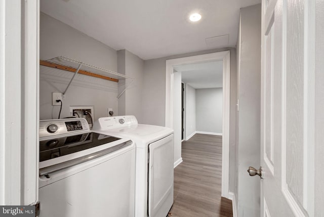 washroom with laundry area, baseboards, washing machine and clothes dryer, and wood finished floors