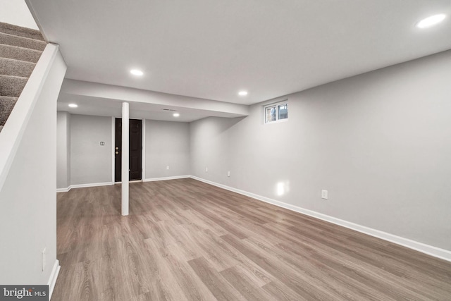 basement featuring recessed lighting, wood finished floors, baseboards, and stairs