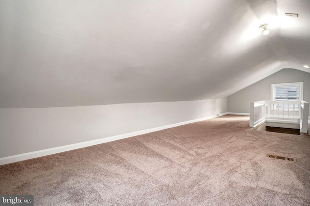 additional living space featuring baseboards, visible vents, vaulted ceiling, and carpet flooring