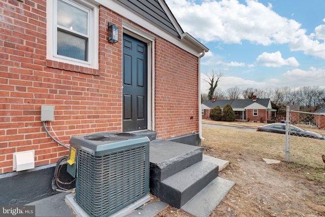 doorway to property featuring central AC and brick siding