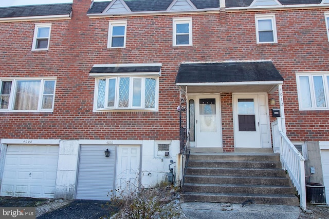 exterior space featuring brick siding, an attached garage, and central AC unit