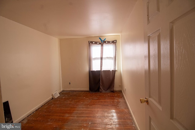 spare room with wood-type flooring and baseboards