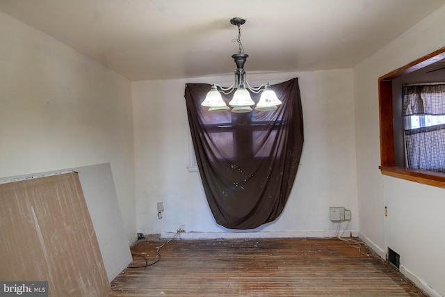 dining room featuring wood finished floors, visible vents, baseboards, and an inviting chandelier