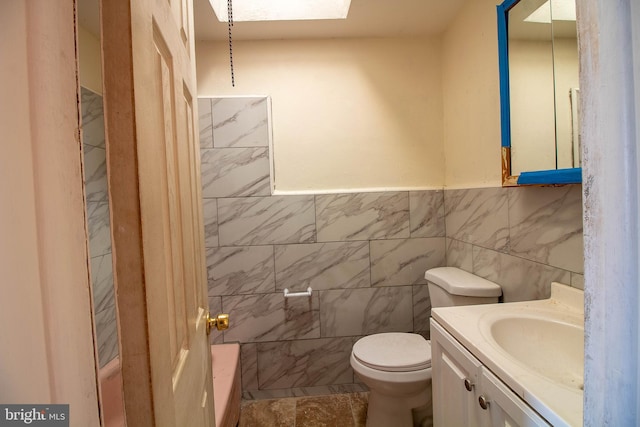 bathroom featuring vanity, toilet, and tile walls