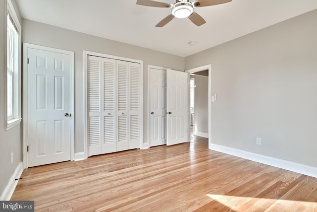 unfurnished bedroom with ceiling fan, light wood finished floors, two closets, and baseboards