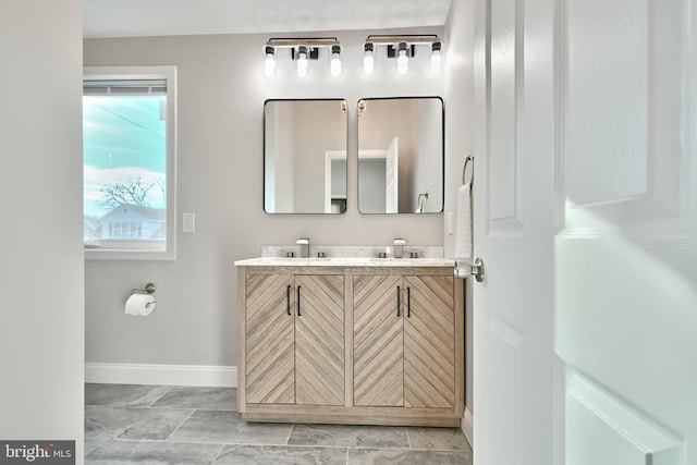 bathroom featuring double vanity, baseboards, and a sink