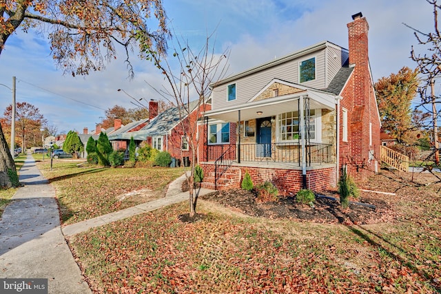 bungalow-style home featuring brick siding, a porch, and a chimney