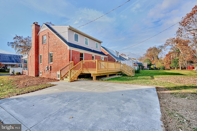 view of side of property with a deck, a yard, brick siding, and a chimney