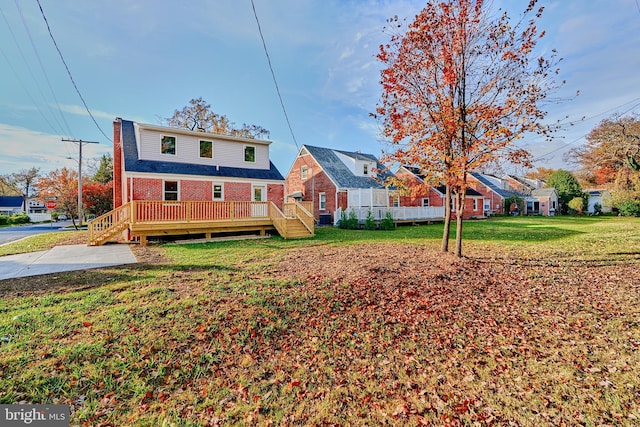 back of property featuring a wooden deck, a chimney, a lawn, and brick siding