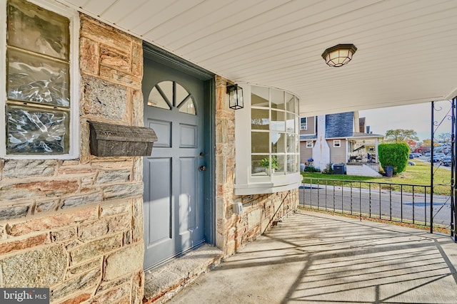 doorway to property featuring covered porch and stone siding