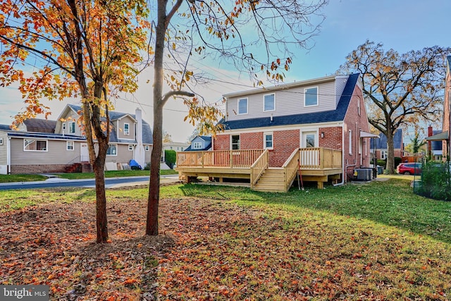 rear view of property with brick siding, a lawn, central AC unit, a deck, and a residential view