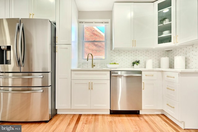 kitchen with light countertops, appliances with stainless steel finishes, a sink, and white cabinetry