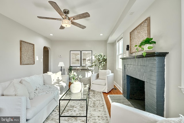 living room featuring arched walkways, a fireplace, recessed lighting, and wood finished floors