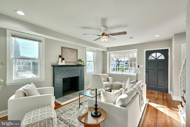 living room with recessed lighting, a brick fireplace, baseboards, and wood finished floors