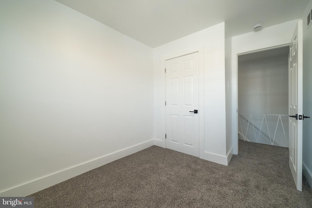 unfurnished bedroom featuring dark colored carpet, visible vents, and baseboards