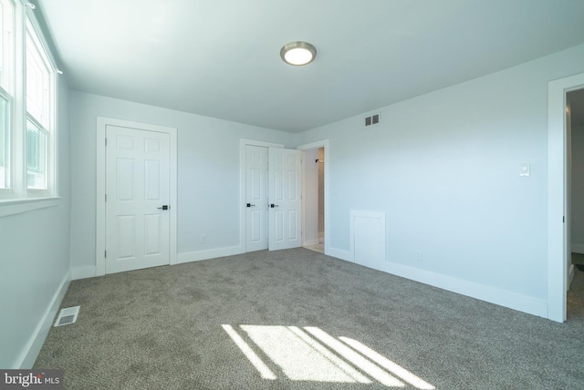 unfurnished bedroom with carpet floors, visible vents, and baseboards