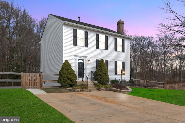 view of front of house with a yard, fence, and a chimney