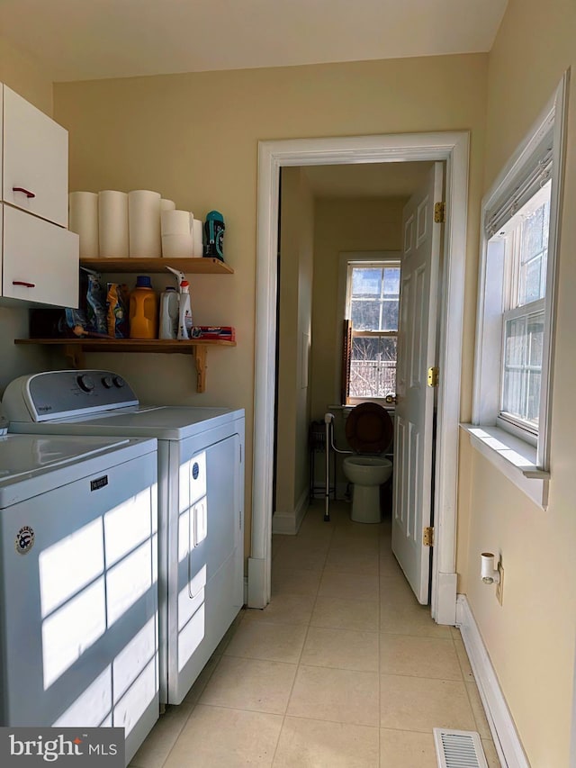 washroom with light tile patterned floors, laundry area, separate washer and dryer, visible vents, and baseboards