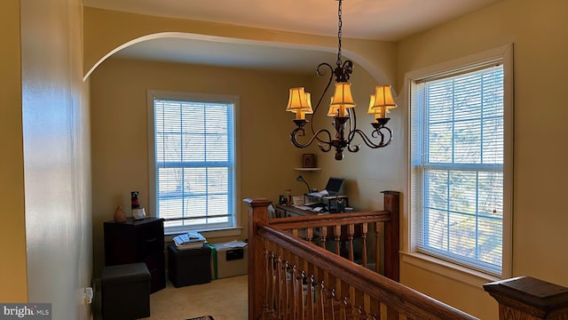 corridor featuring carpet floors, arched walkways, plenty of natural light, and an upstairs landing