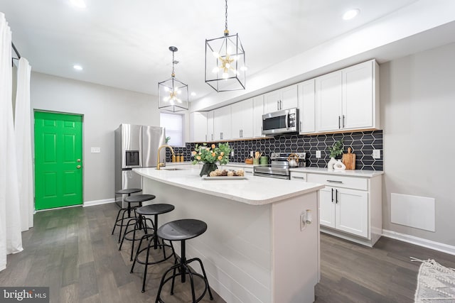 kitchen featuring appliances with stainless steel finishes, a kitchen island with sink, light countertops, and white cabinetry