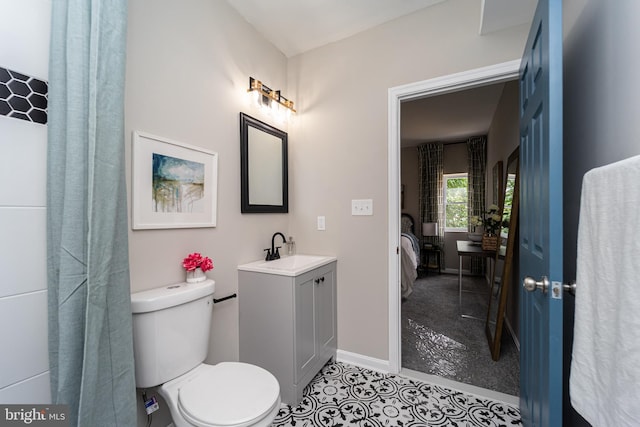 bathroom with baseboards, vanity, toilet, and ensuite bathroom