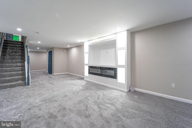 unfurnished living room with carpet, recessed lighting, a glass covered fireplace, baseboards, and stairs