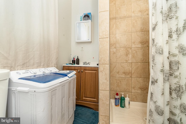 full bathroom featuring washer / dryer, a tile shower, and a sink