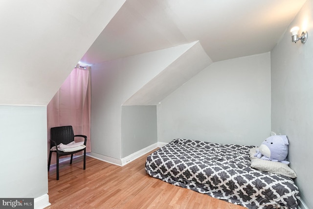 bedroom featuring lofted ceiling, baseboards, and wood finished floors