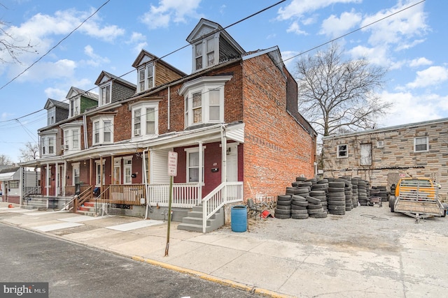 view of property featuring covered porch and brick siding