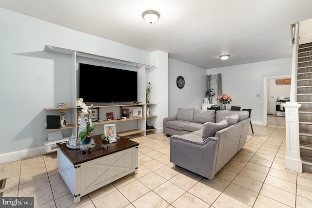 living area featuring light tile patterned flooring, stairway, and baseboards