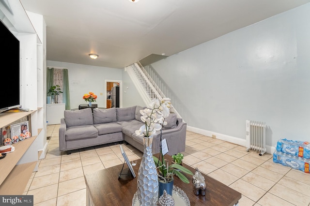 living room with light tile patterned floors, radiator heating unit, stairs, and baseboards