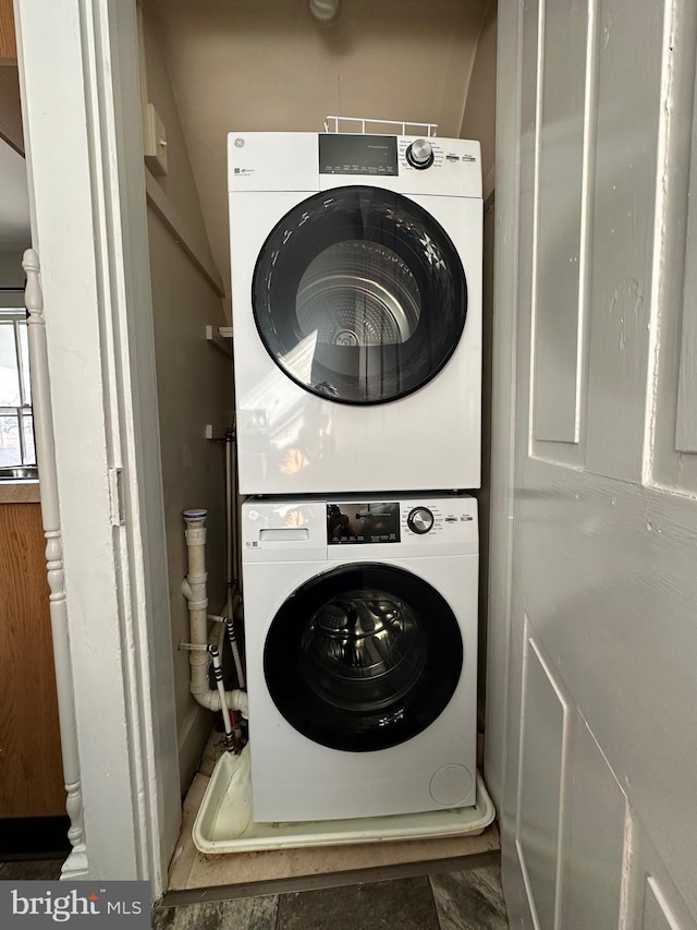 washroom with stacked washer and clothes dryer and laundry area